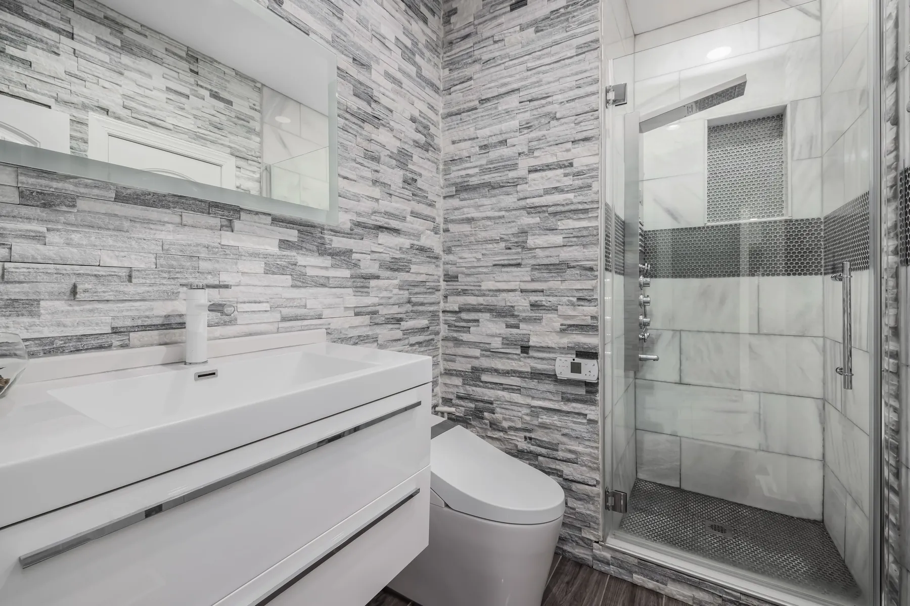 Modern bathroom with a stone-tile walk-in shower and glass enclosure